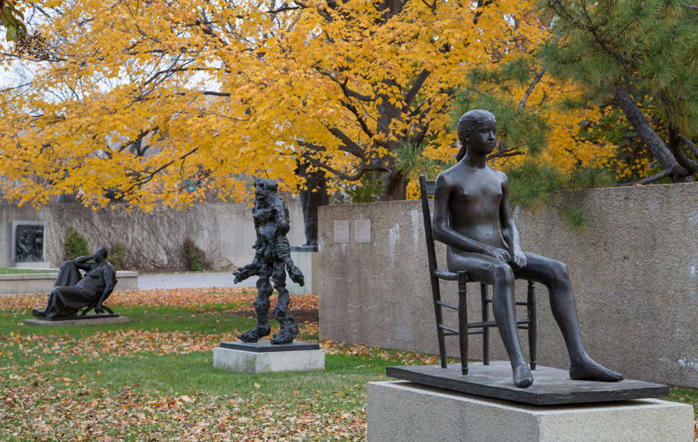 Hirshhorn Sculpture Garden in the fall. Yellow foliage amongst three bronze sculptures.