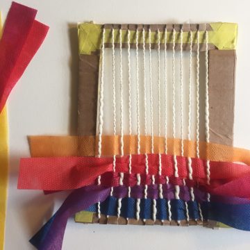 Weaving is halfway finished. Brightly colored weft—the horizontal yarns—follow the over and under pattern.