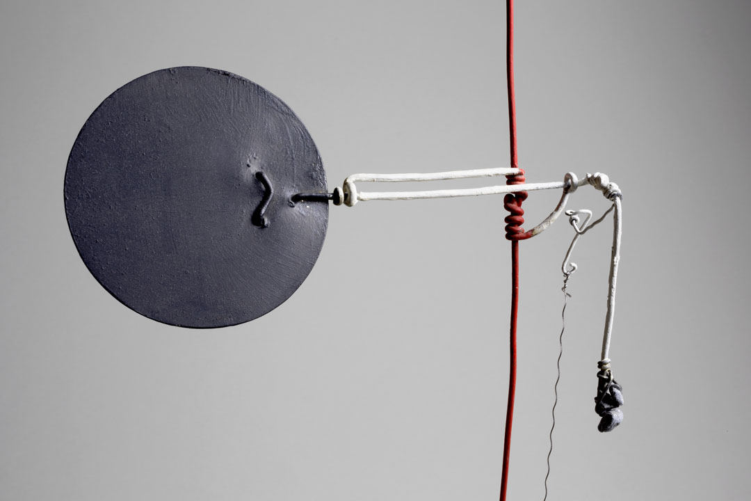 A black metal disc extends from a vertical red wire. A wire lever extends outward, which can be pulled to operate the disc.