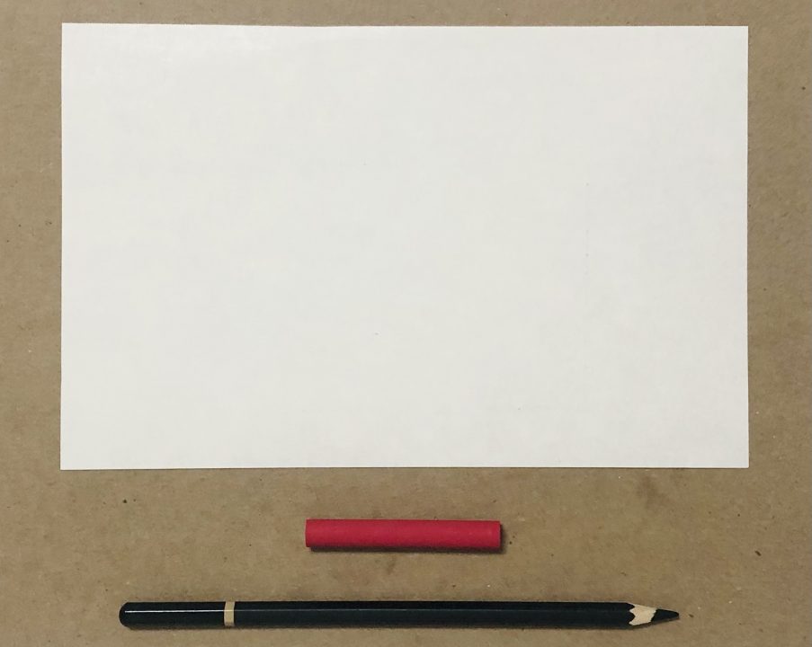 An arrangement of white paper, red crayon, and black pencil.