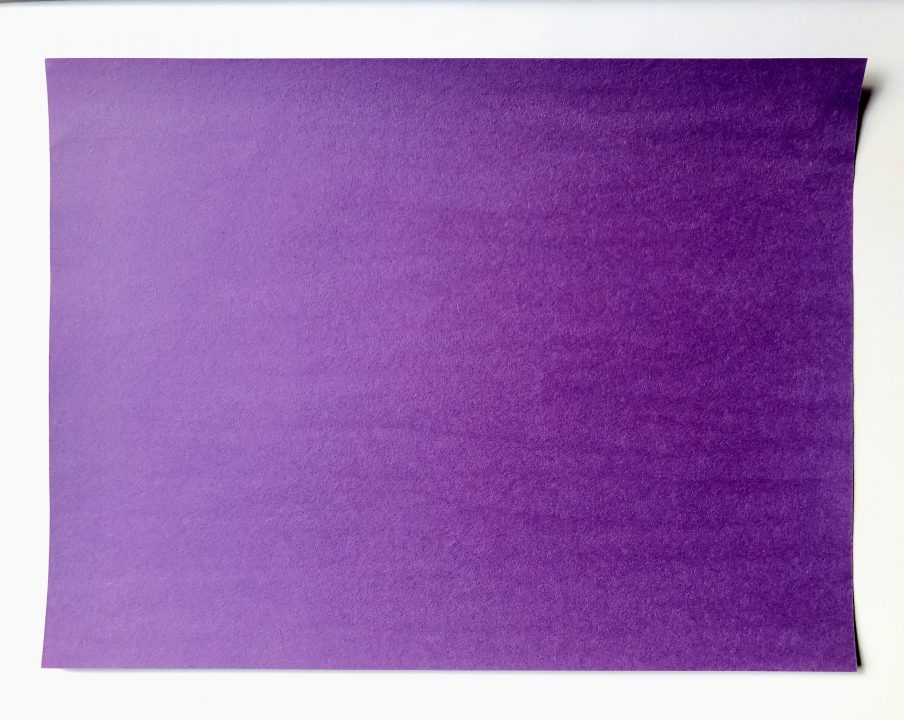  A piece of purple construction paper sits in the middle of a white background.