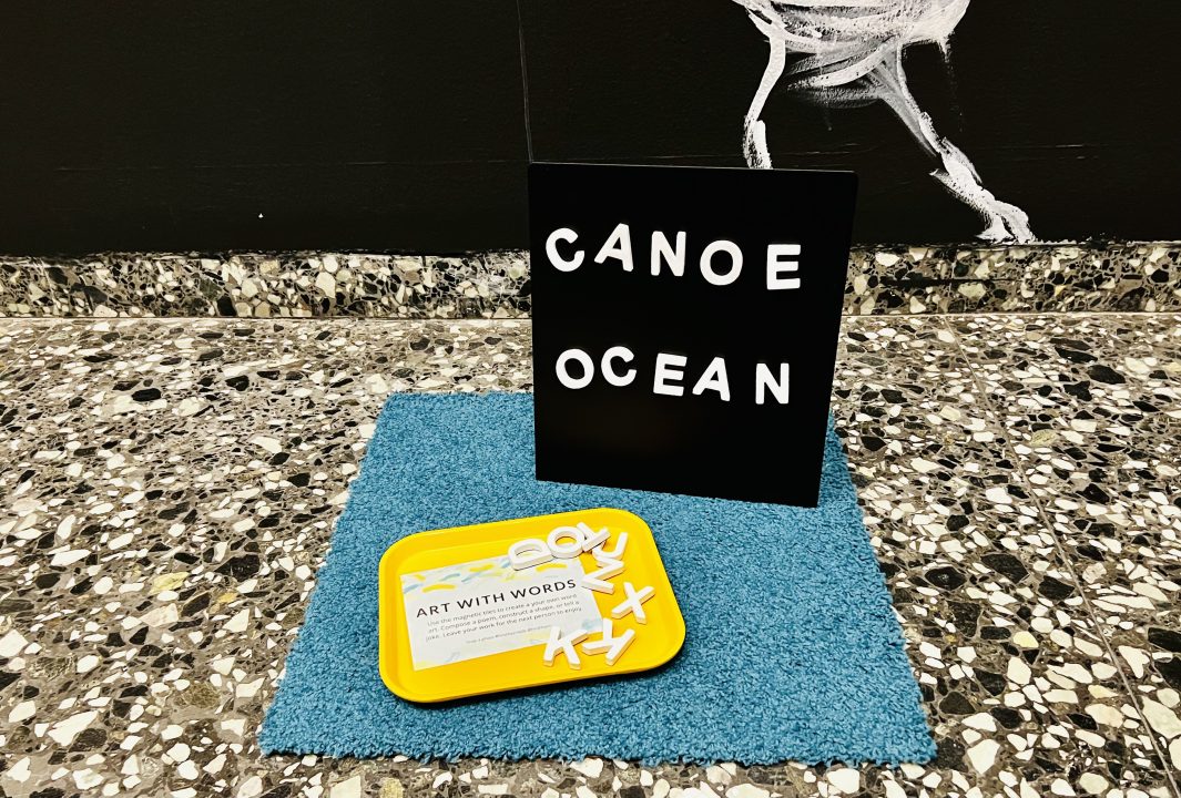 An Art Cart display sits on the floor in front of the entrance to Laurie Anderson,