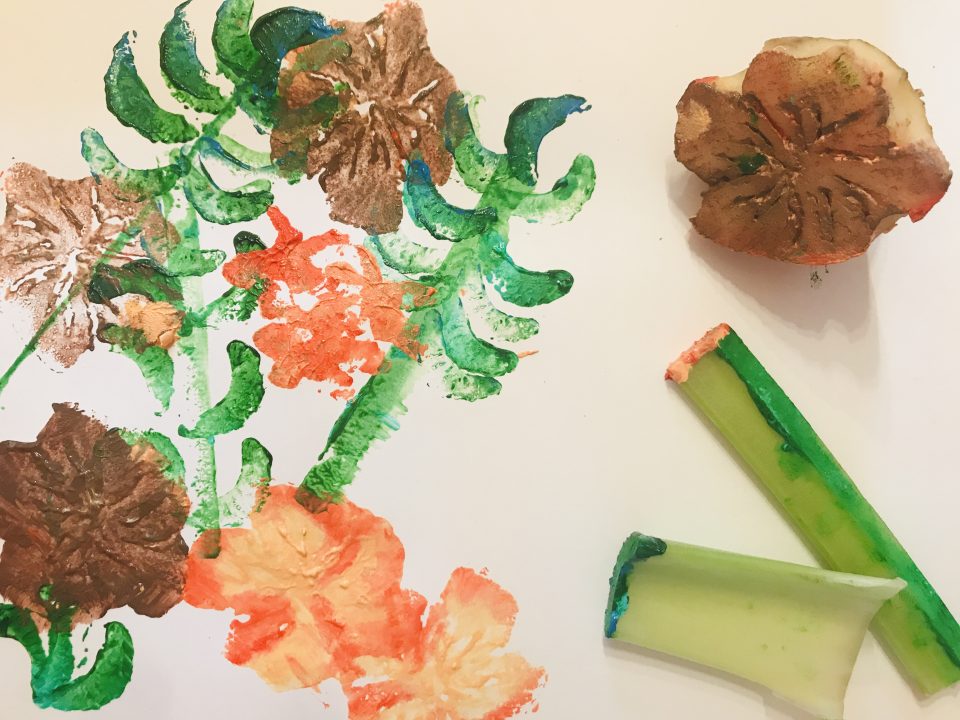 On the left, a colorful green and peach flower print. To the right, paint stained pieces of celery and potato rest.