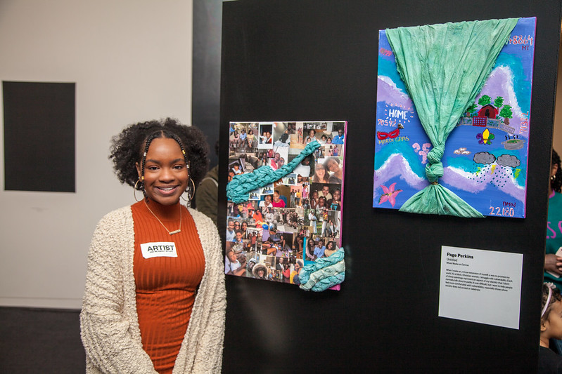 Teen stands proudly next to her artwork on display