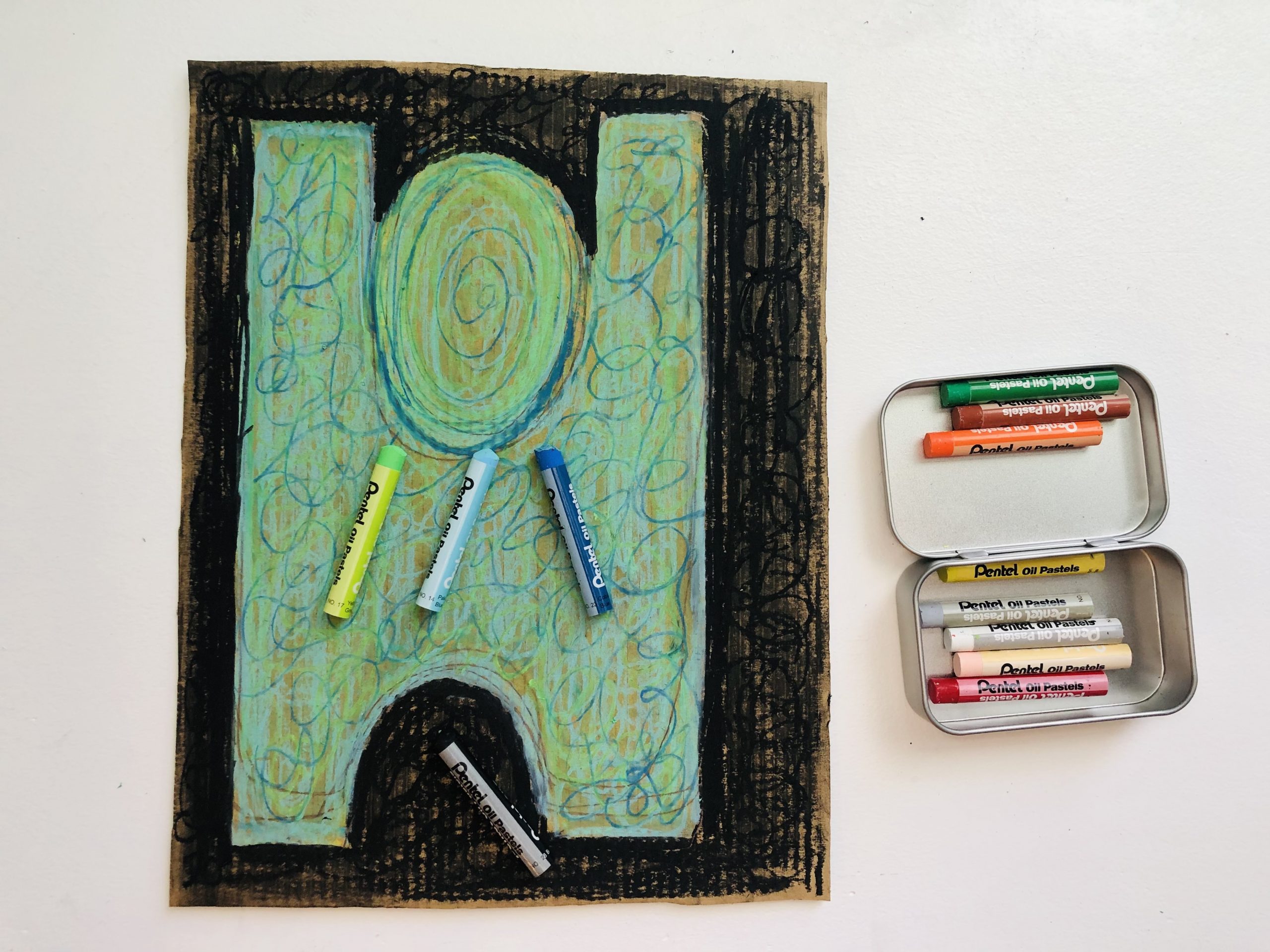 A colorful abstracted figure consisting of shades of lime green, sky blue, and a darker blue against a black background. Oil pastels of the same colors rest on top of the artwork with a tin of oil pastels to the right.