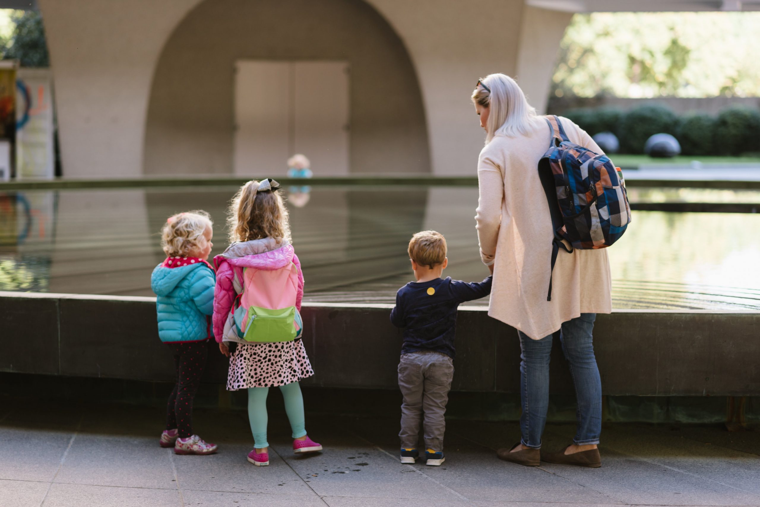 Three children stand at the base of the fountain in the Hirshhorn's plaza.