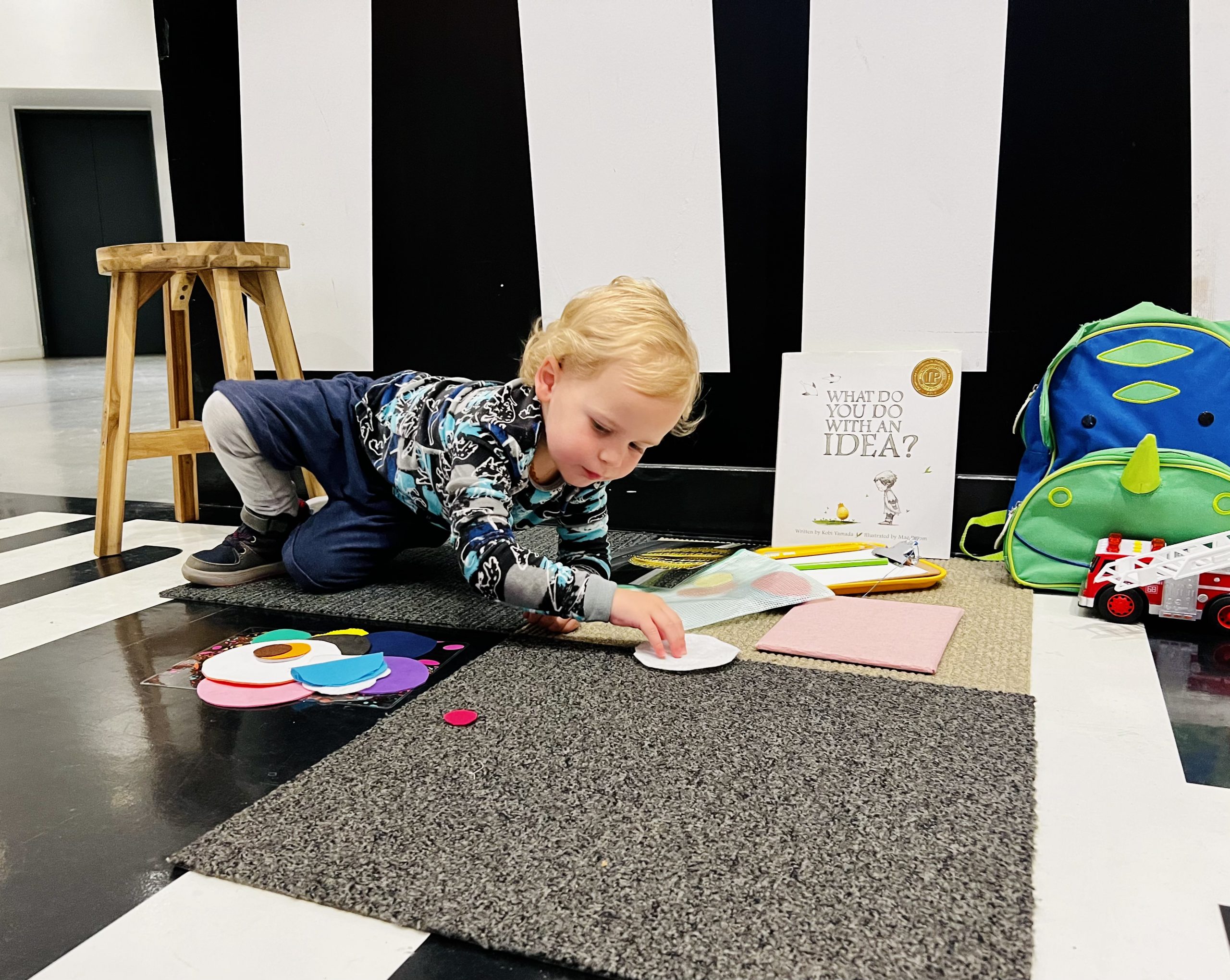 A blonde boy sits on a grey mat in the Hirshhorn's lower level.