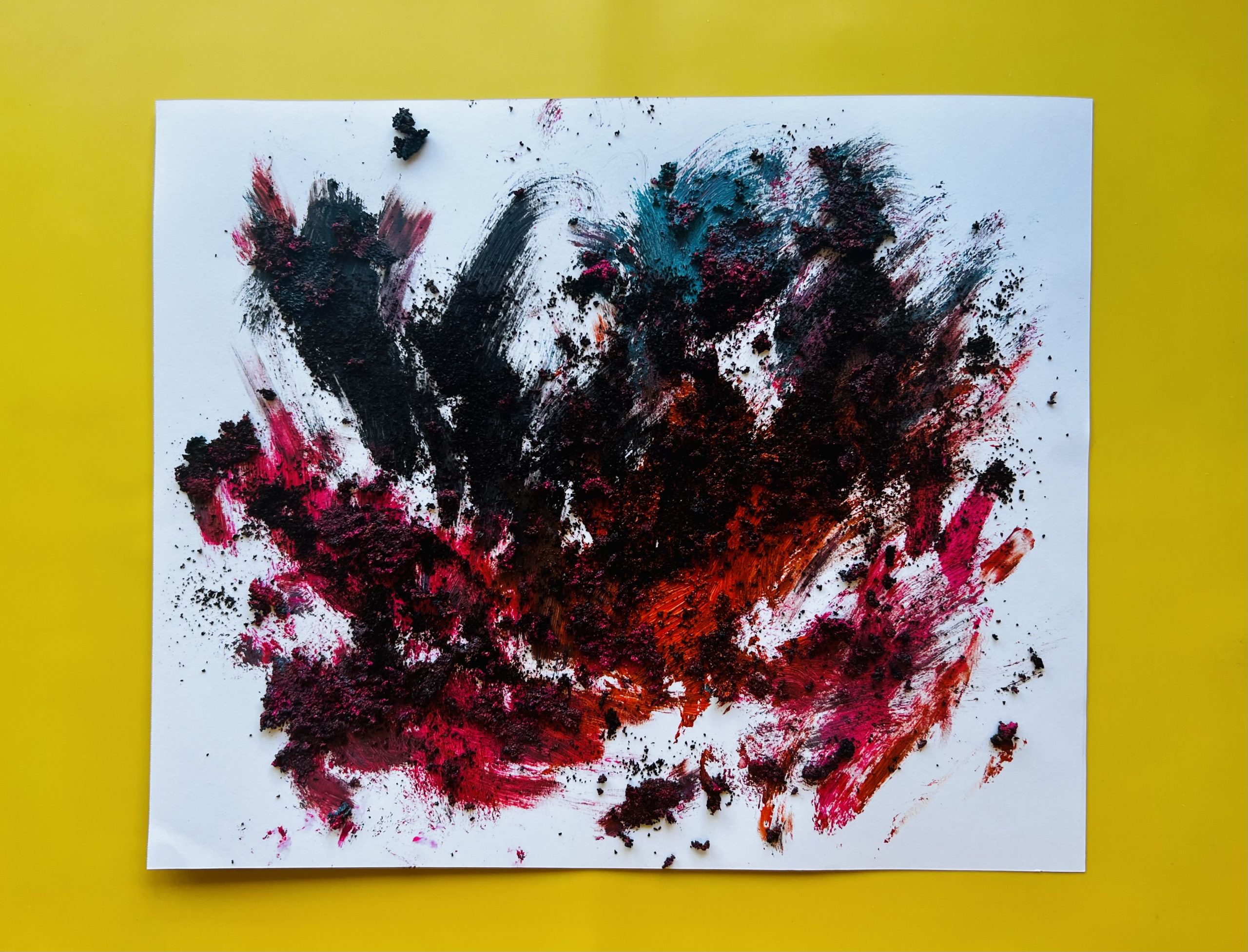 Abstract painting on yellow background consisting of hot pink, teal, orange, and black paints mixed with coffee grounds. Finger marks can be seen throughout the work.