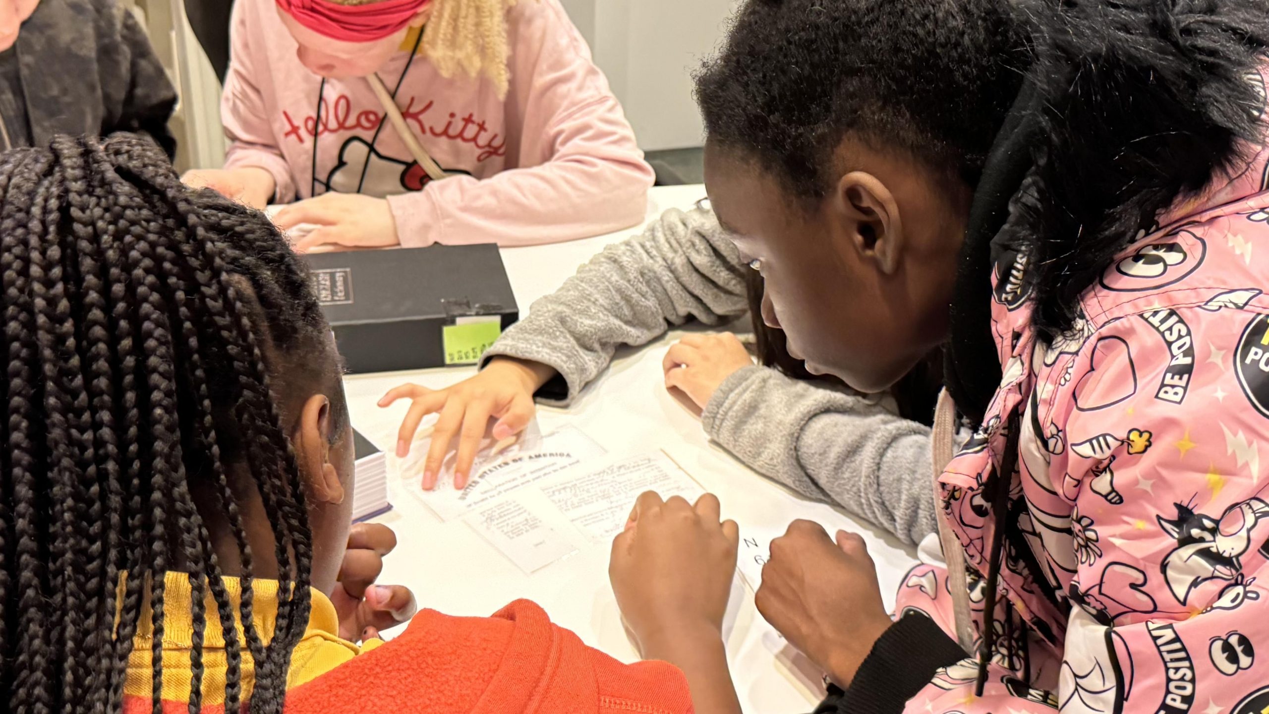 Children hunched over desk participating in group activity