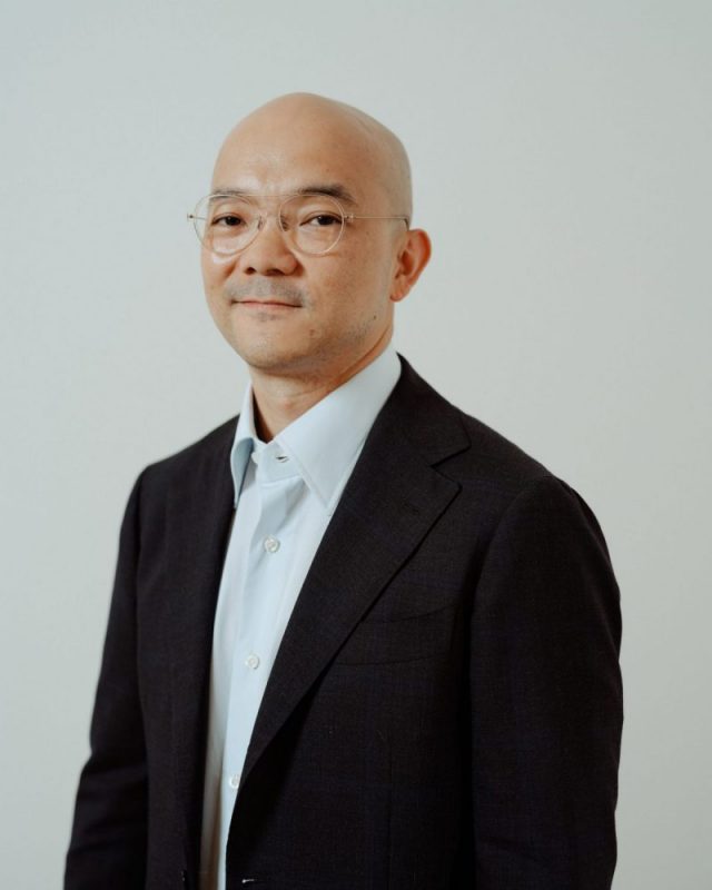 portrait of Aaron Seeto, a man wearing a black suit with a white shirt underneath