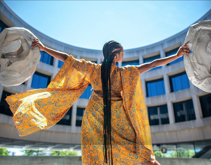 a woman wearing a yellow kimono and long cornrowed braids