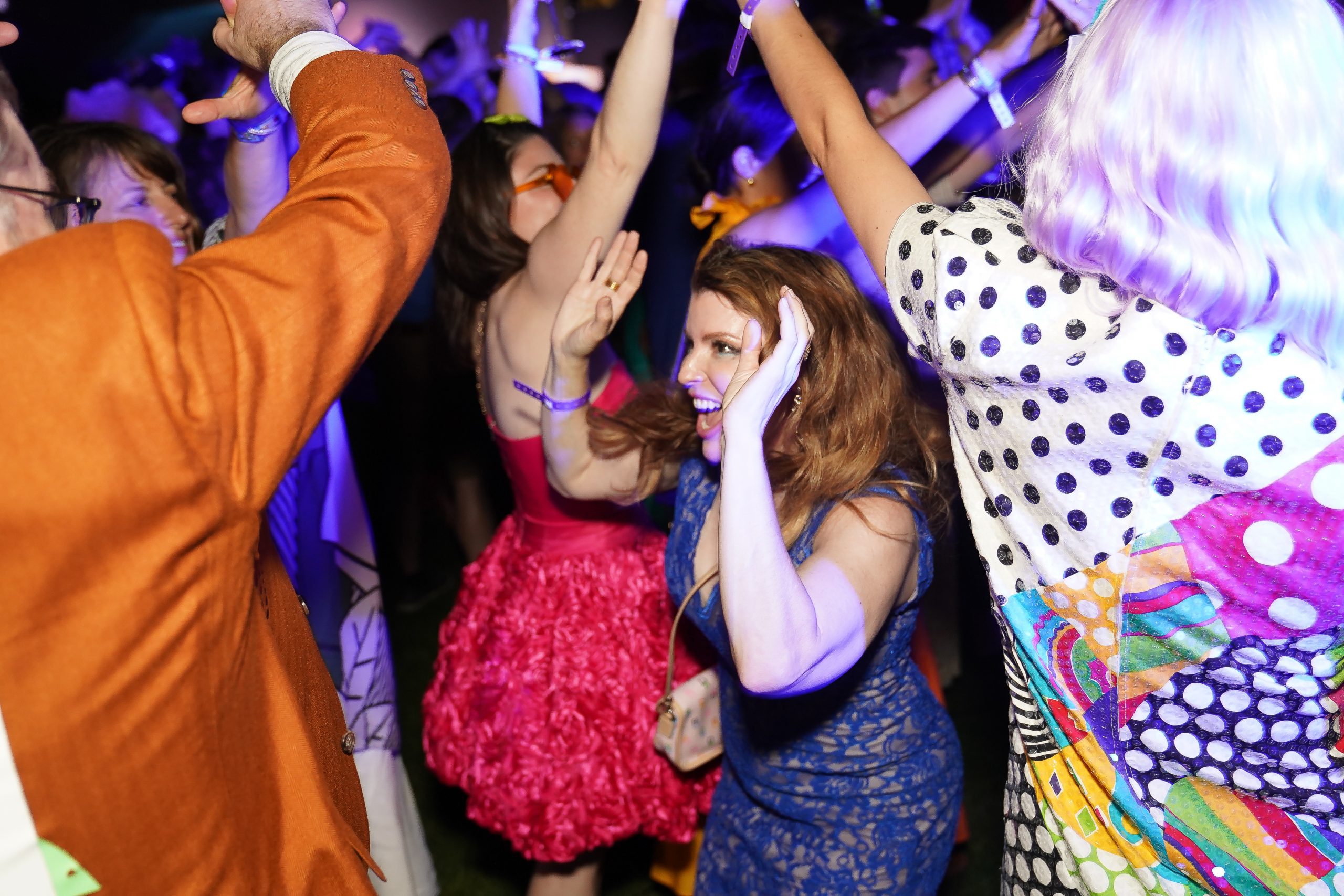 a woman in a blue dress at the hirshhorn ball with her hands up in the middle of the dancefloor