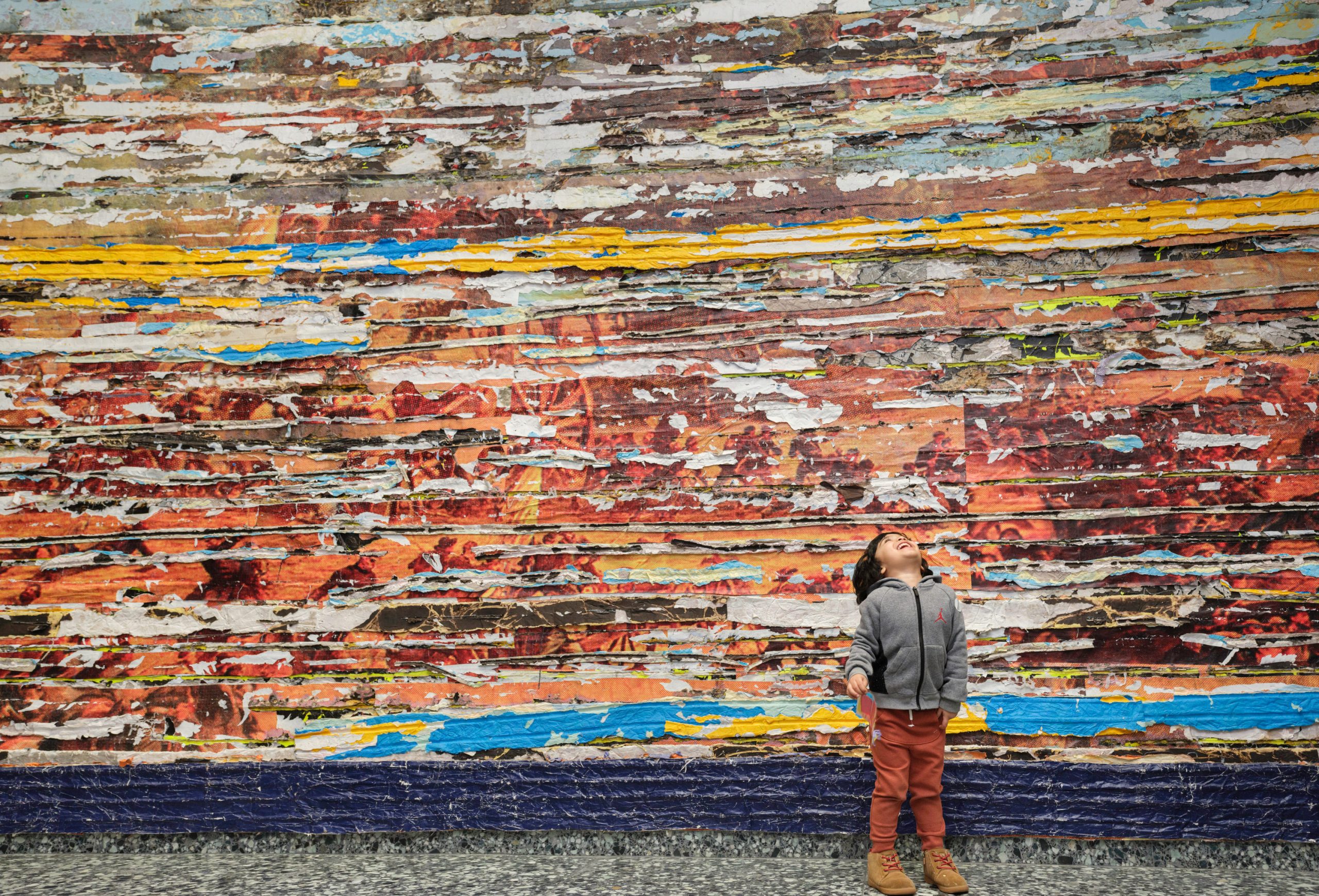 a child infront of a large scale abstract paper painting looks up
