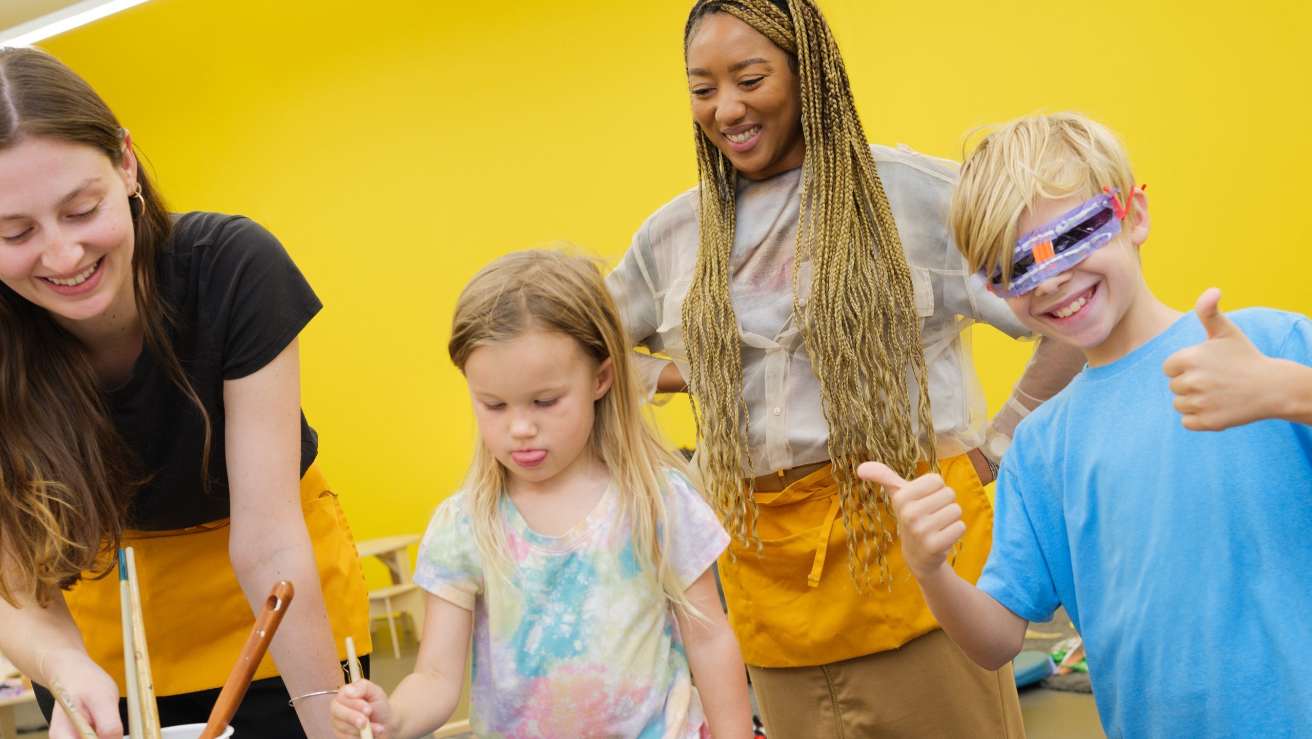 Two children with two instructors working on a painting