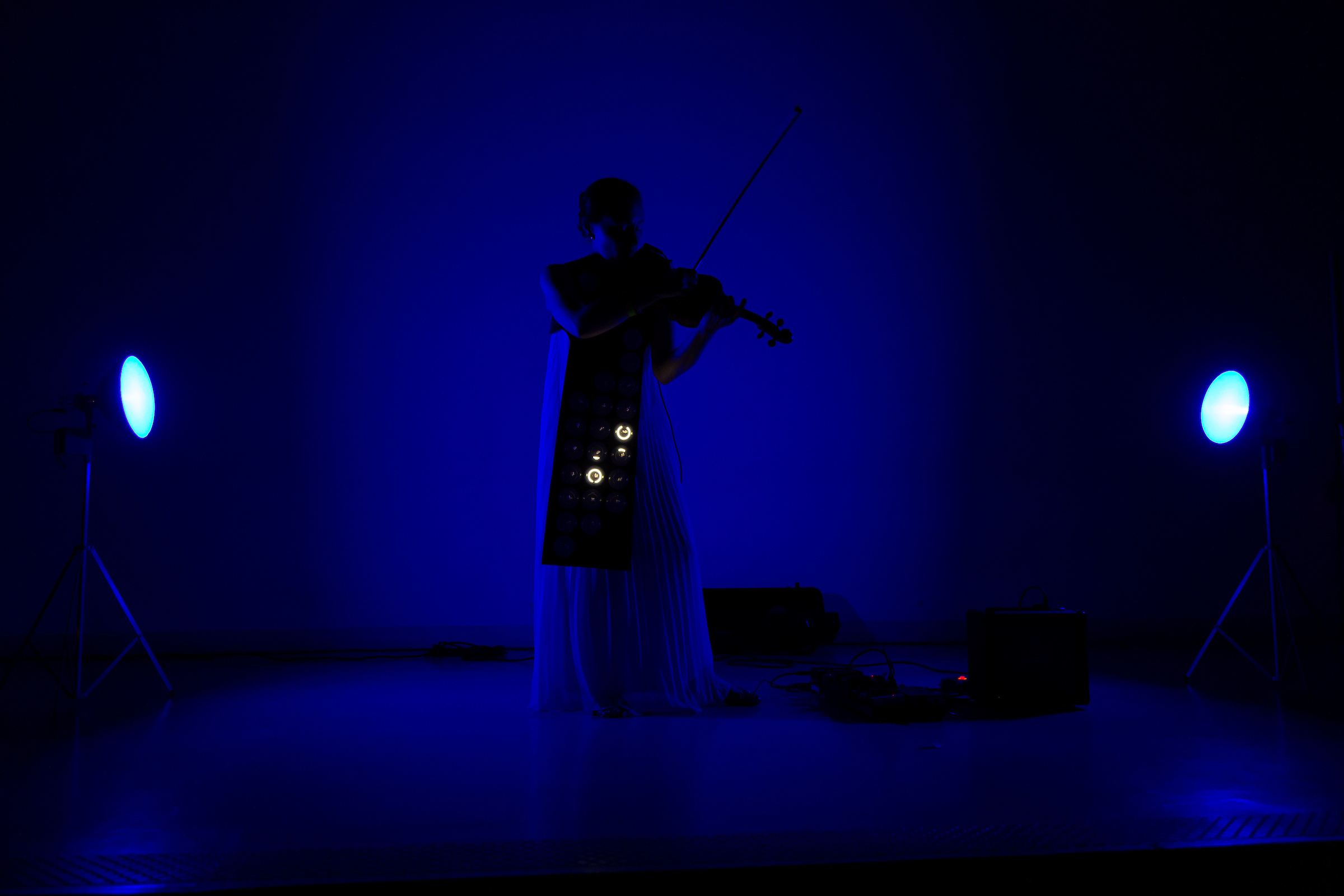a woman plays a violin in a dark blue lit room