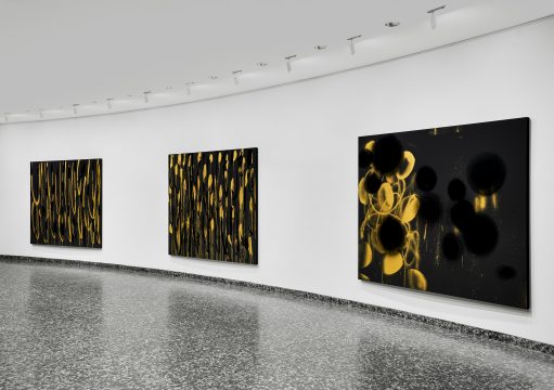 three large black and yellow abstract paintings are displayed on a white wall